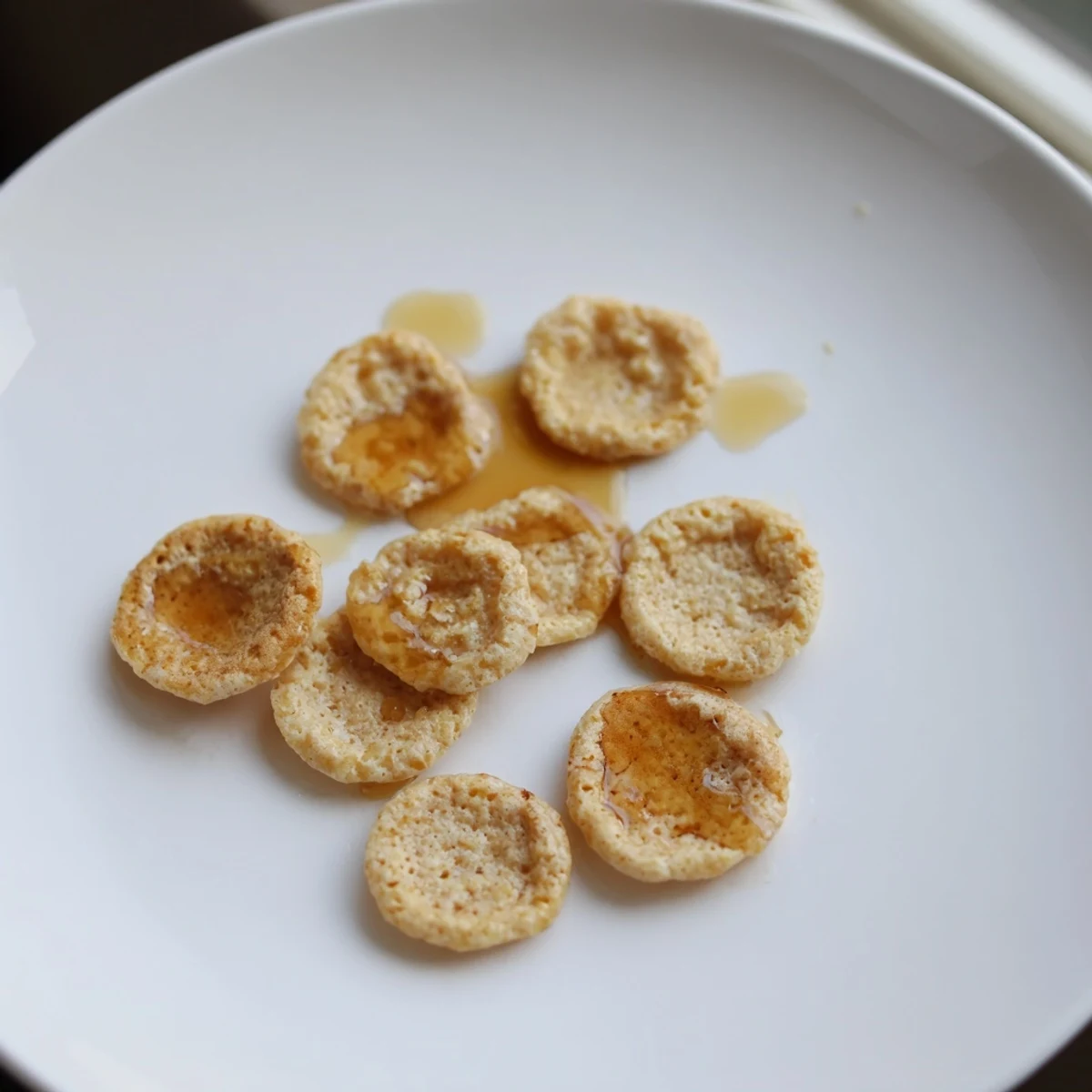 Golden, fluffy pancake cereal, perfect for a fun breakfast, served with a drizzle of syrup.