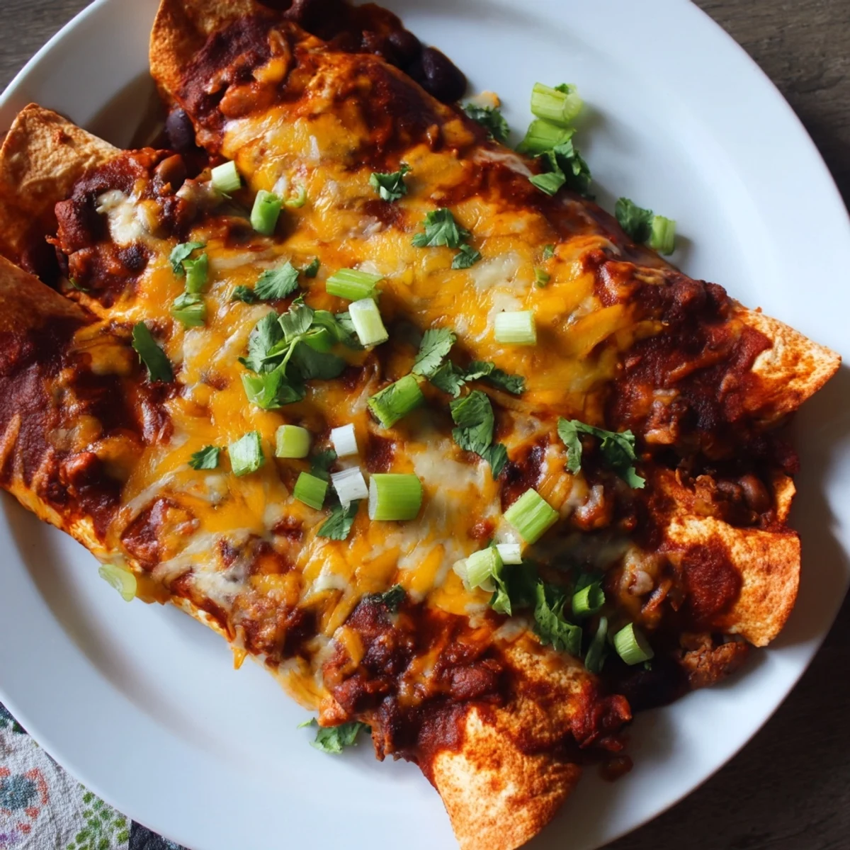 Steaming hot Cheesy Bean Enchiladas with bubbly, golden cheese and a rich, red sauce, ready to eat.