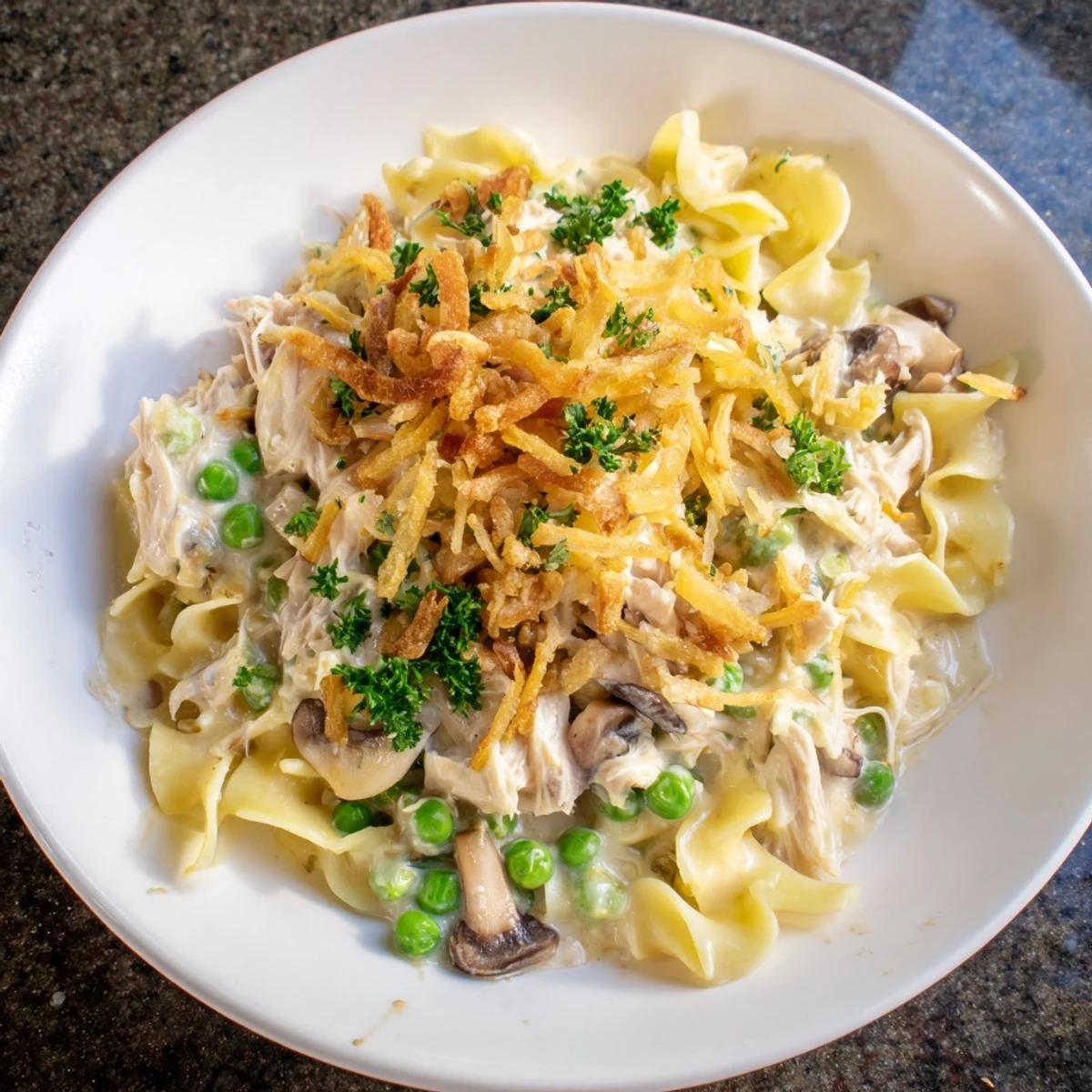 A close-up shot of a bubbling, creamy tuna noodle casserole topped with crispy fried onions.