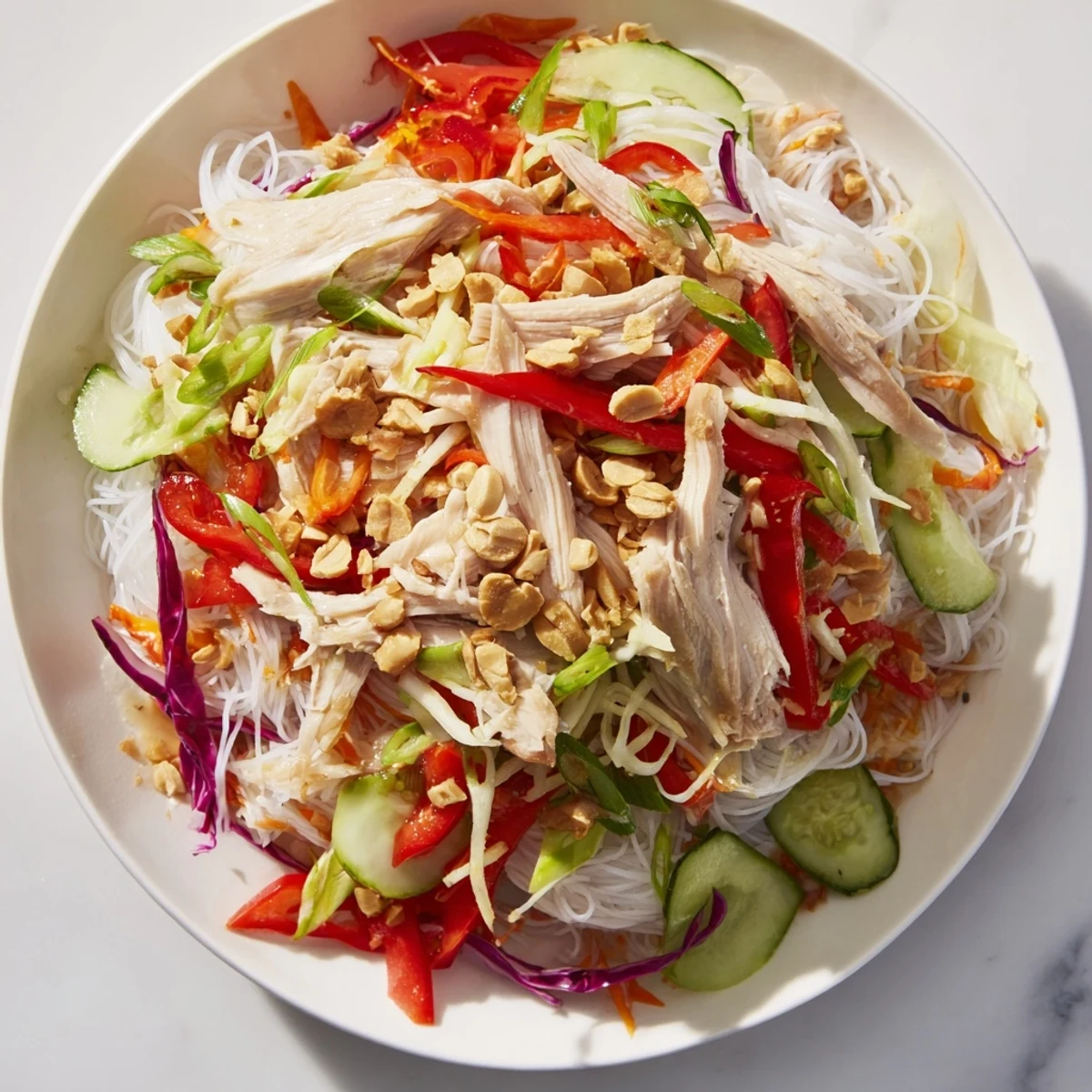 A colorful bowl of Vietnamese Crunch Noodle Salad with glistening shredded chicken and fresh herbs.