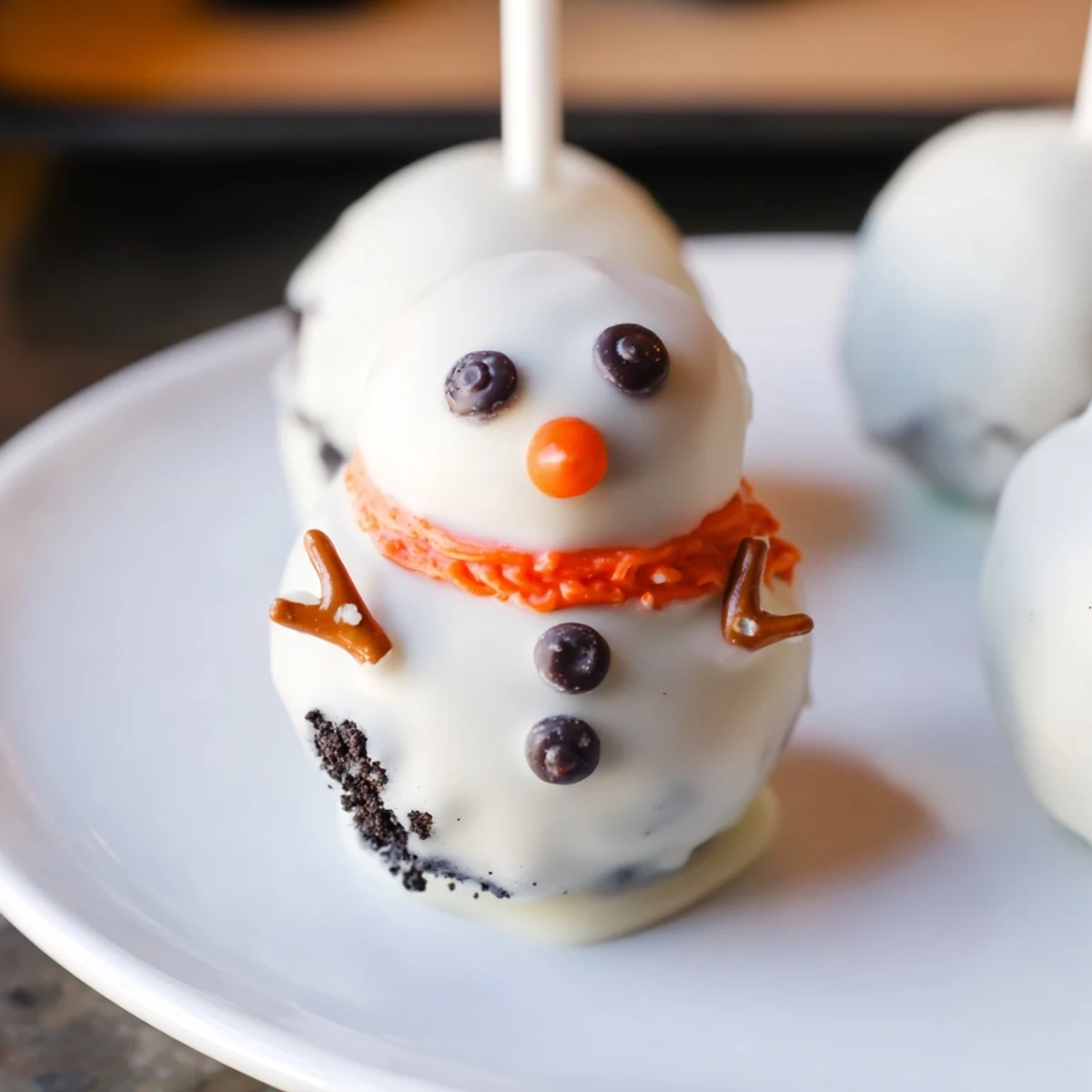 Melted white chocolate covers the delicious Oreo Snowman Cake Pops, decorated with cute features.