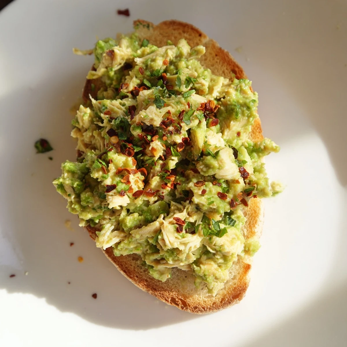 Crisp rustic bread holds a hearty scoop of pea and chicken salad, garnished with feta and a bright lemon zest finish.