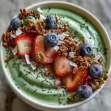 A creamy matcha yogurt smoothie bowl topped with fresh berries, crunchy granola, and chia seeds for a vibrant breakfast.