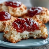 Soft, buttery clotted cream cookies topped with jewel-like strawberry jam, offering a delightful British-inspired dessert.