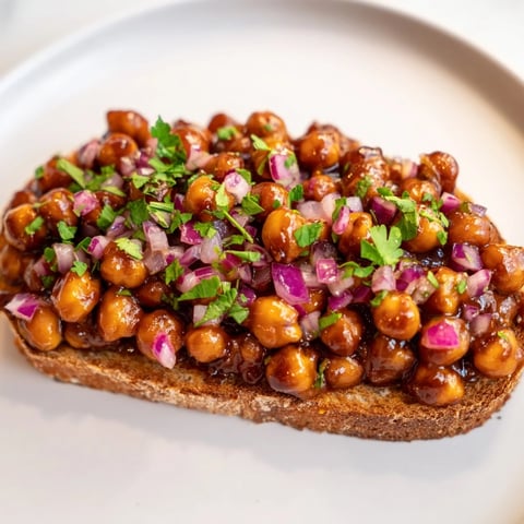 Golden-brown BBQ Chickpeas on Toast piled high, savory vegan lunch with fresh cilantro garnish.