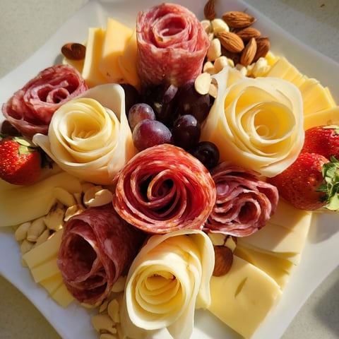 A Meat and Cheese Rose Garden Board with salami roses and colorful fruits looks delicious.