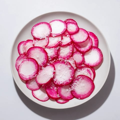 Crisp radish slices glistening with sea salt, ready to eat as an easy, healthy snack.