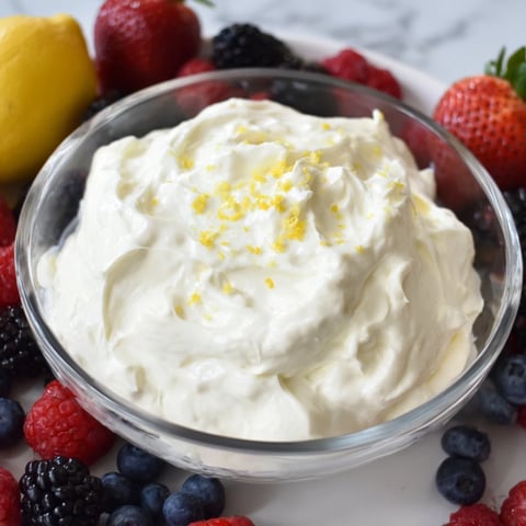 Fluffy cream cheese fruit dip with vibrant berries, a sweet and refreshing dessert snack to enjoy.