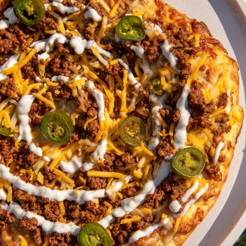 Ground Beef Taco Pizza, topped with melted cheese and jalapeños, ready for serving.