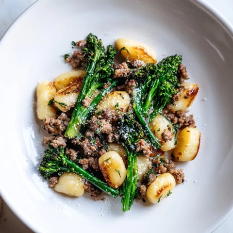 Golden sheet pan gnocchi bake with crispy edges, Italian sausage, and Parmesan cheese melting.