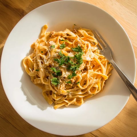 Close-up of Sriracha Honey Pasta showing creamy orange sauce coating fettuccine, garnished with fresh parsley and parmesan.