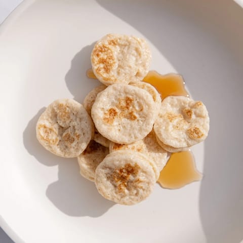 Miniature pancake cereal: a bowl filled with tasty, bite-sized pancakes ready to be enjoyed.