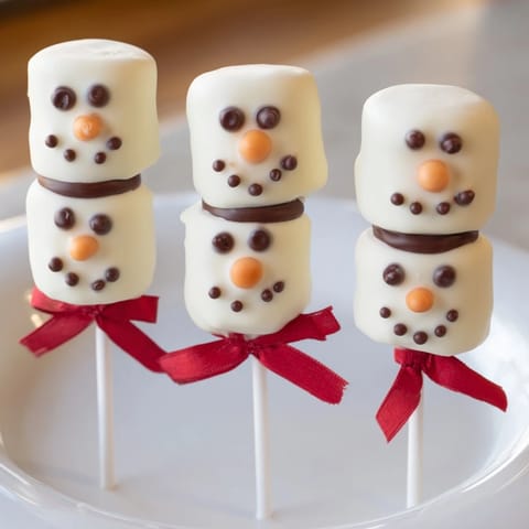 Festive Express Snowman Marshmallow Pops: a close-up of cheerful, decorated holiday dessert on a stick.
