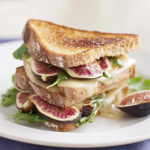 A close-up shot of a Fig, Brie & Arugula Grilled Cheese, perfectly toasted with crispy bread.