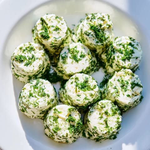 Fresh, herb-coated goat cheese "Mossy Stones," a delightful, whimsical appetizer for sharing and fun.