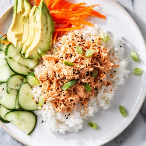 A visually appetizing Spicy Canned Salmon Rice Bowl showcases creamy salmon atop fluffy rice, garnished with fresh scallions.