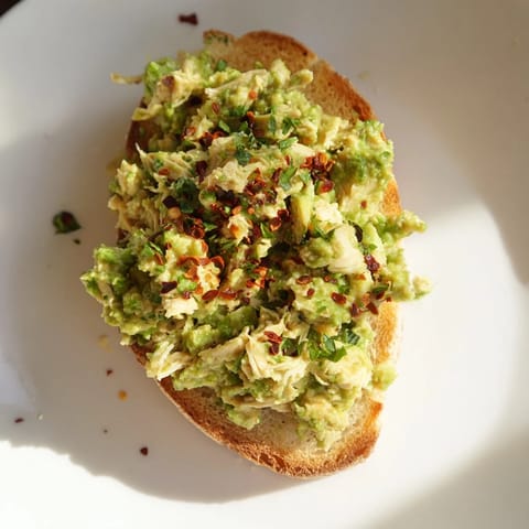 Crisp rustic bread holds a hearty scoop of pea and chicken salad, garnished with feta and a bright lemon zest finish.