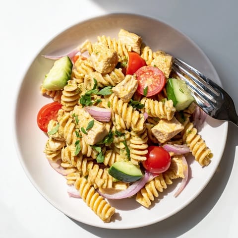 Fresh Honey Mustard Chicken Pasta Salad served on a bed of mixed greens with cherry tomatoes and red bell peppers.