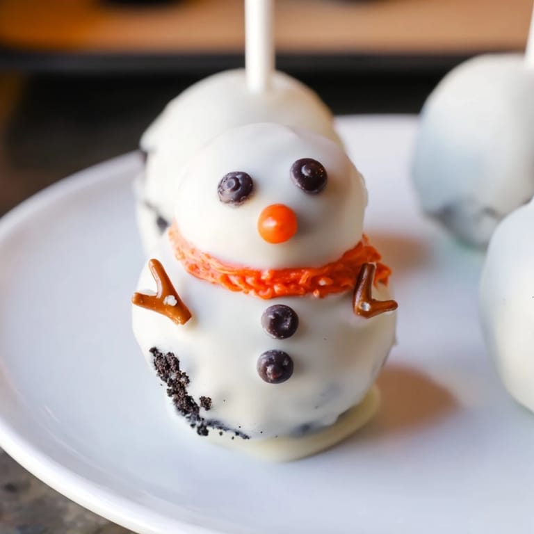 Melted white chocolate covers the delicious Oreo Snowman Cake Pops, decorated with cute features.