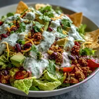 A colorful taco salad bowl layered with seasoned turkey, crisp romaine, black beans, corn, and creamy Greek yogurt ranch dressing.